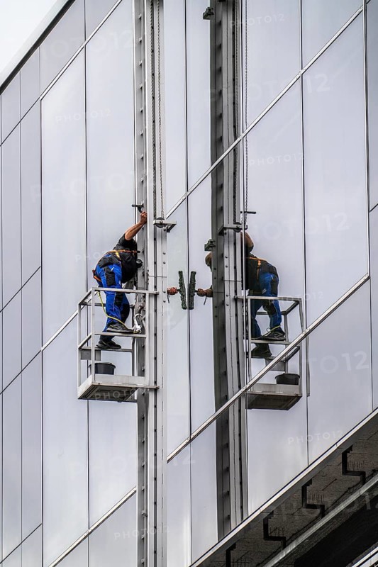 Window cleaner, facade cleaning, window cleaning, on a glass facade in Düsseldorf, ladder cage from the roof