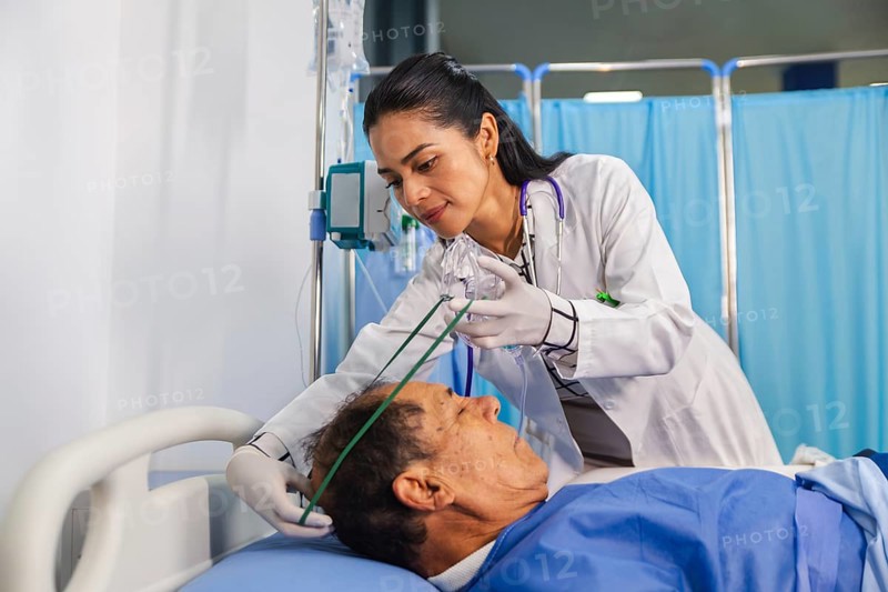 A compassionate doctor attentively assists a patient in a hospital room, ensuring proper care with medical equipment and oxygen support, highlighting dedication in healthcare settings