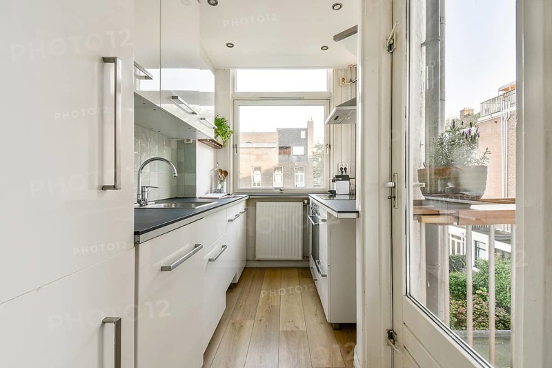 A contemporary kitchen featuring sleek cabinetry, natural light flooding in from large windows, and wooden flooring. A perfect blend of style and functionality