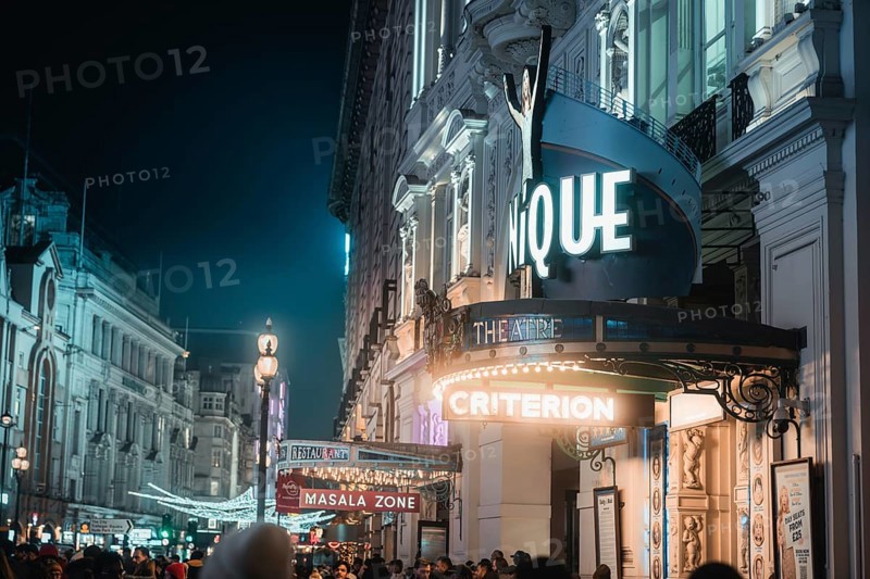 Urban night scene with illuminated theatre and crowd, New Year's Eve London, Great Britain