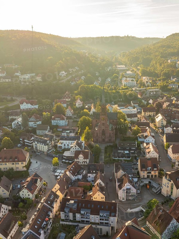 Idyllic close-up of a village with church, surrounded by hills and trees in the light of the sunset, Nagold, Black Forest, Germany