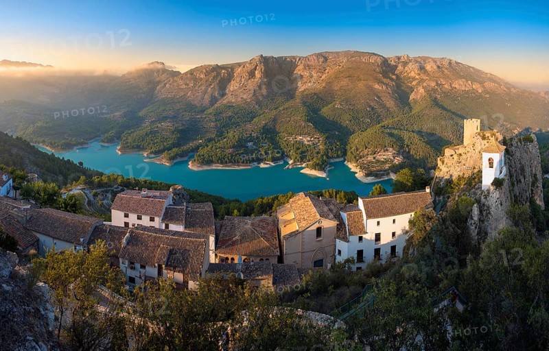 Stunning aerial and panoramic views of the medieval castle, whitewashed village, and turquoise reservoir in the picturesque valley of Guadalest, Alicante, Spain