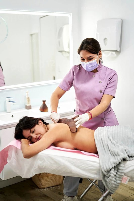 A qualified therapist provides a soothing massage to a client at a beauty salon specialized in aesthetic medicine. The tranquil environment promotes relaxation and wellness