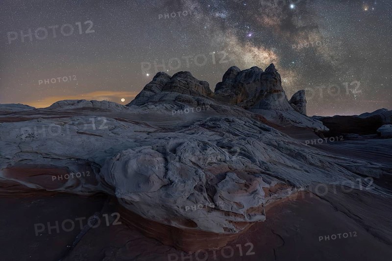 A breathtaking view of Utah's desert landscape under a star-studded Milky Way. No people in this serene nighttime scene composed of rocky formations and a clear view of celestial wonders