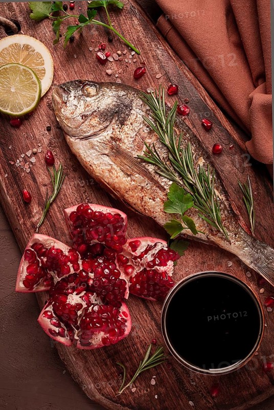 Fried dorado fish, with spices and herbs, on a wooden board, pomegranate sauce, close-up, no people