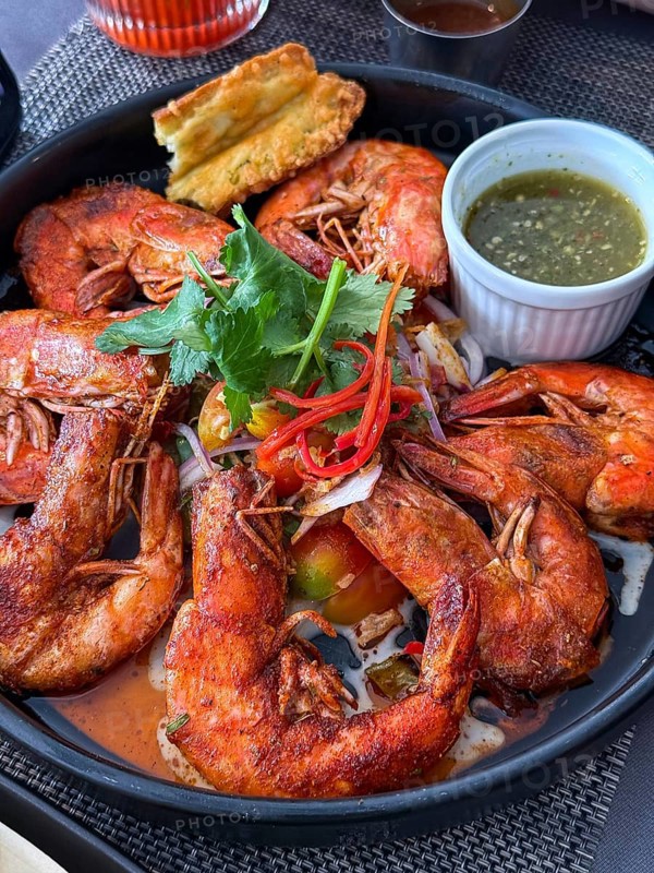 A flavorful dish of seasoned fried shrimp served with a spicy dipping sauce in a Thai cafe setting