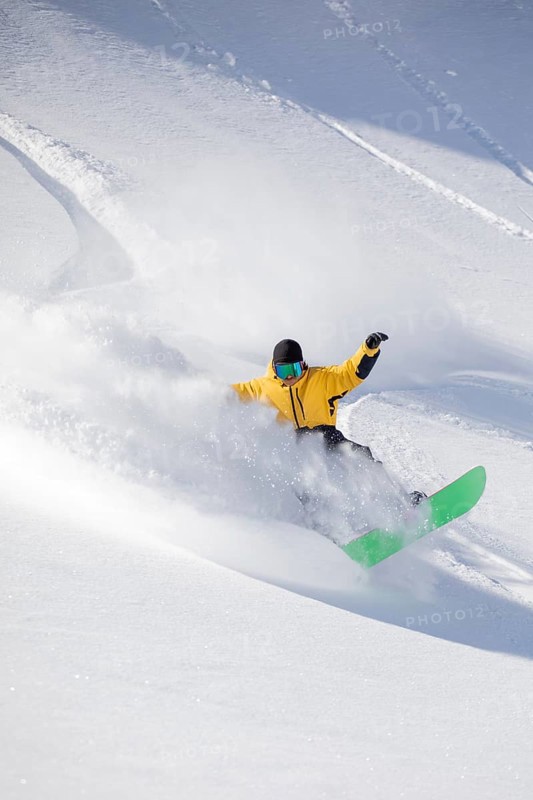 A snowboarder in a vibrant yellow jacket expertly carves through fresh powder on a snowy mountain slope, creating a dynamic spray of snow and an exciting action scene