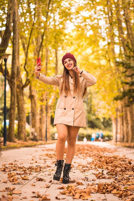 Portrait of a beautiful woman in autumn next to a forest in nature making a video call