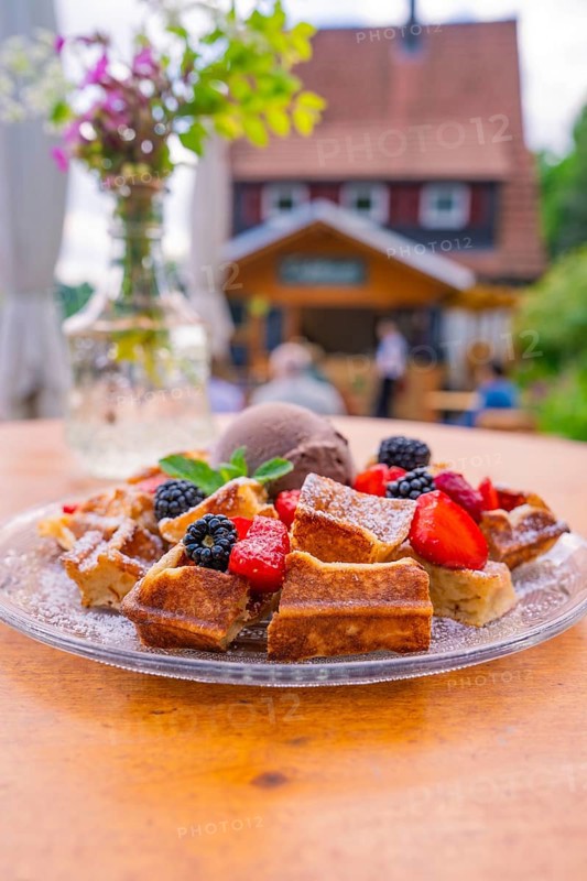 Waffles with berries and ice cream on a table with a café in the background, Cafehäusle Calw, Black Forest, Germany