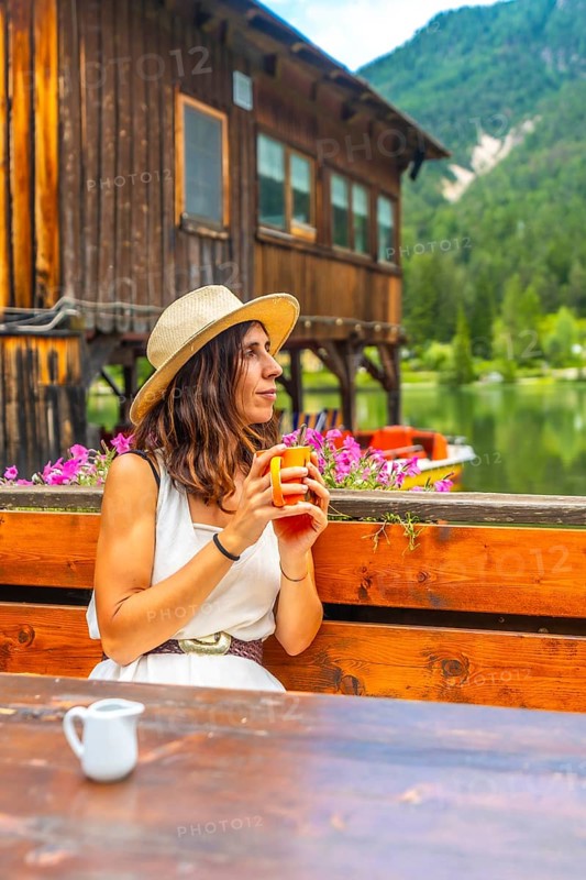Woman relaxing at lake dobbiaco with a mug, enjoying the mountain landscape in the dolomites