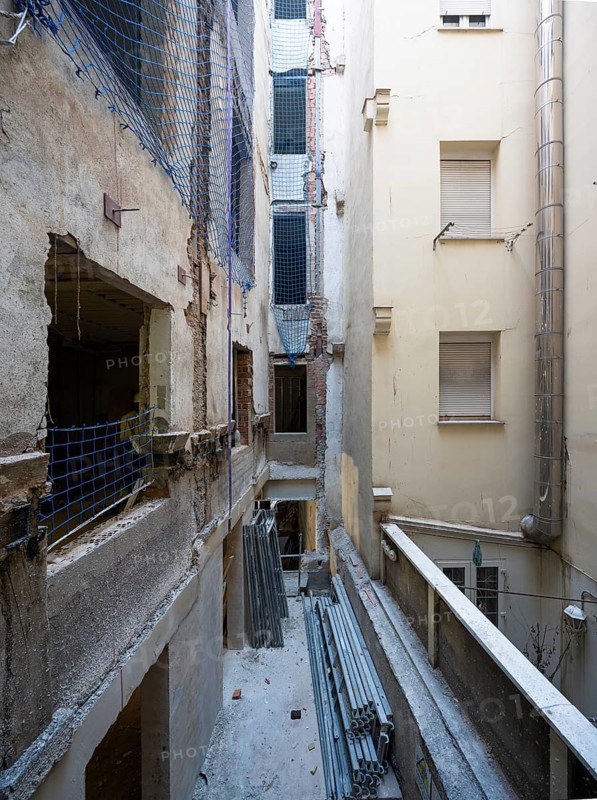 A detailed view of an urban renovation project, with exposed walls, construction materials, and safety netting, illustrating the ongoing progress and structural work
