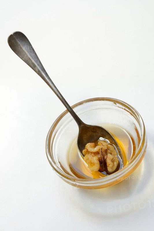 Walnut with spoon in blossom honey, honey and walnut