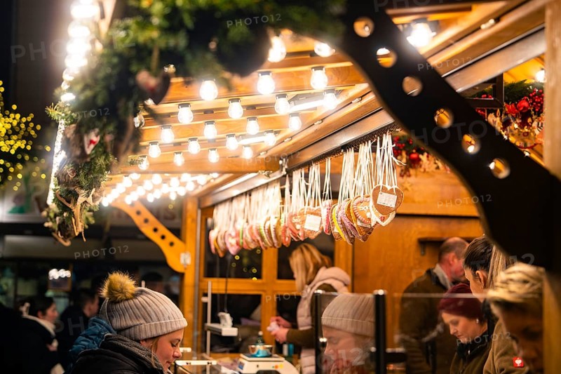 A Christmas stall with gingerbread hearts, surrounded by lights and customers, Christmas market Ludwigsburg, Germany