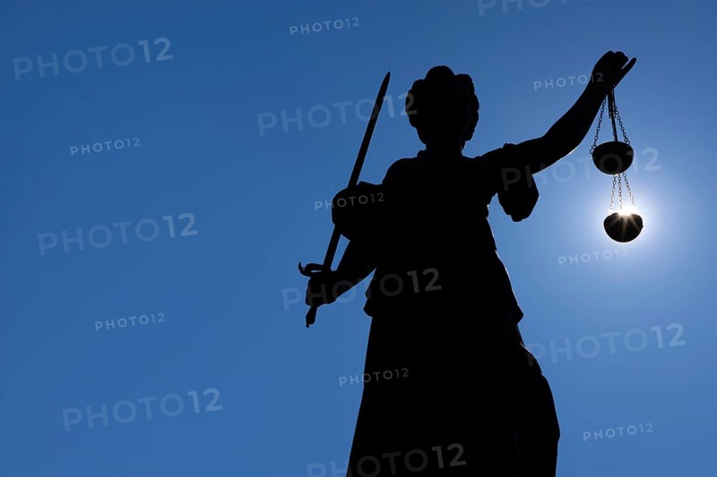 The silhouette of the Justitia statue on the Römerberg in Frankfurt am Main is silhouetted against the sun. It looks as if the sun is lying in her scales of justice, Frankfurt am Main, Hesse, Germany
