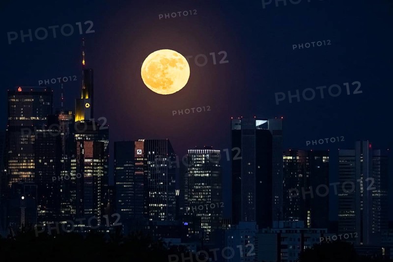 The full moon passes behind the Frankfurt banking skyline, Frankfurt am Main, Hesse, Germany