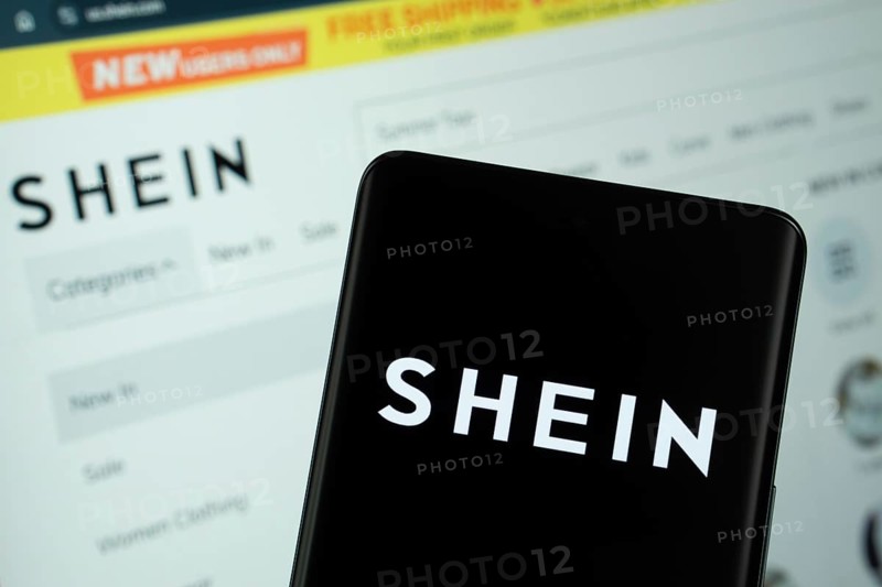 Dhaka, Bangladesh - 18 March 2025: The logo of the shein is displayed on a smartphone screen, and the website shein is visible on a computer screen in the background