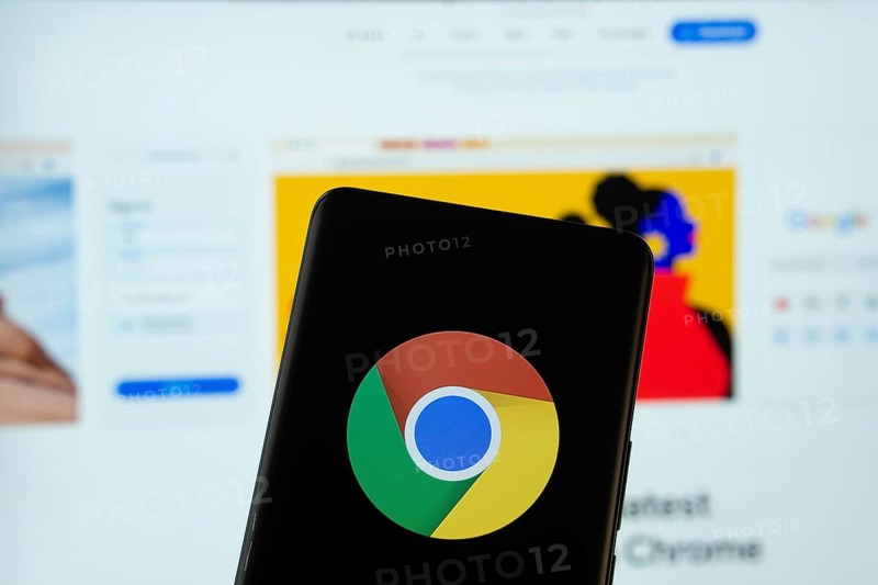 Chrome logo is displayed on a smartphone screen, with the chrome website visible on a computer screen in the background