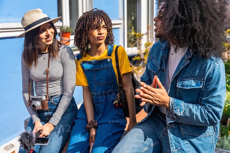 Three young content creators planning video content discussing and sharing ideas sitting in the street