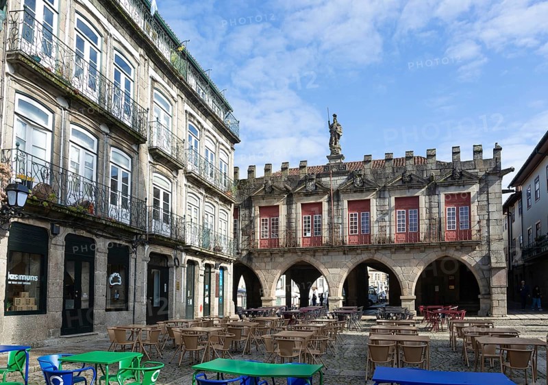 Tables and chairs, historic buildings in Largo da Oliveira square, city of Guimaraes, northern Portugal
