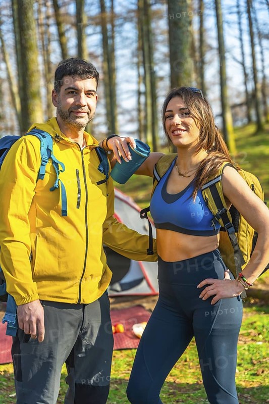 Hikers posing happily near their campsite in the woods, taking a well deserved break from their adventurous trek through nature