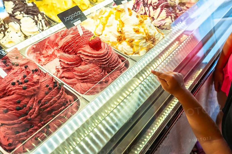 Kid pointing at strawberry ice cream flavor in a gelateria in piran, slovenia, during summer holidays on the adriatic coast