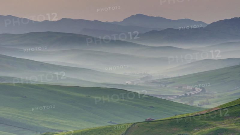 Morning mist, back-to-back hill ranges, green fields, haze, individual houses, Madonie National Park, spring, Sicily, Italy