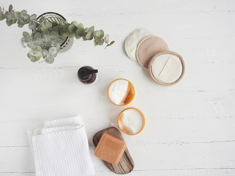 Zero waste organic cosmetics concept flat lay composition with Reusable make-up remover discs, organic soap, cream, glass bottle, white towel and dried eucalyptus leaves