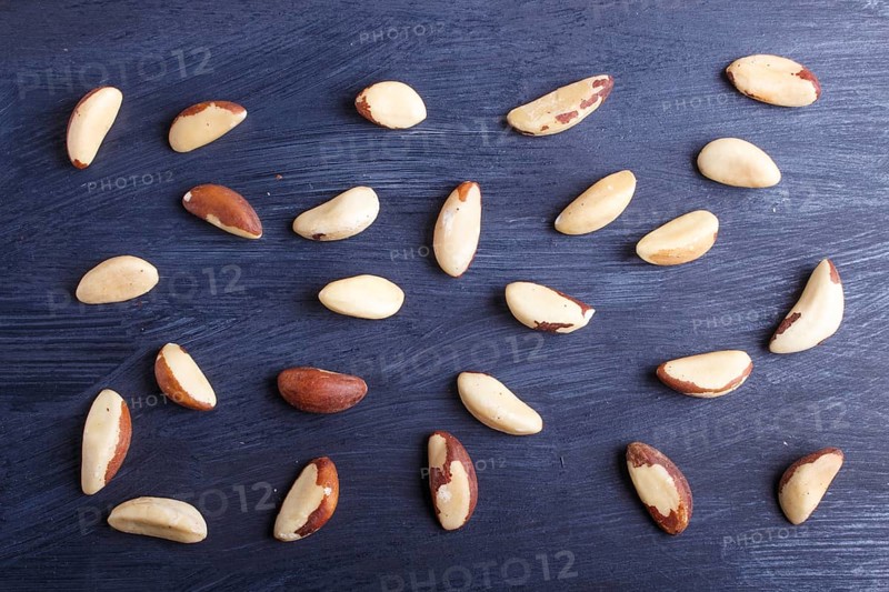 Pattern and texture made from Brazil nuts on black wooden background, flat lay. top view