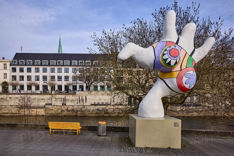 Nana, sculptor Niki de Saint Phalle, polyester sculpture, bench, public rubbish bin, riverside promenade, river Leine, general architecture, diffuse light, milky blue cloudy sky, slightly sunny, Mike-Gehrke-Promenade, Hanover, state capital, Hanover region, Lower Saxony, Germany