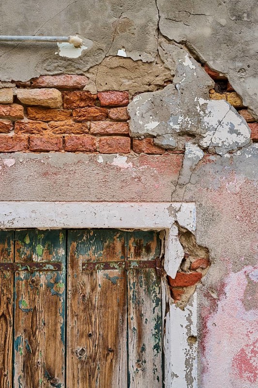 Old crumbling wall and window frame with weathered wood of an old shutter, Burano, Venice Italy