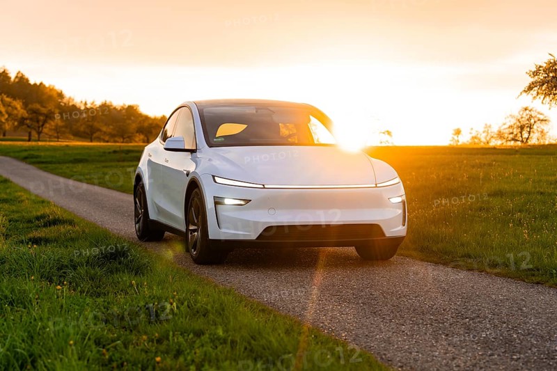A white car driving on a narrow road at sunset, Tesla New Model Y, Germany