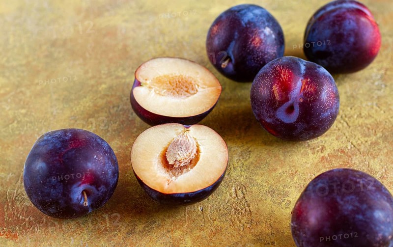 Plums scattered on the table, fresh, top view, yellow-orange background, no people