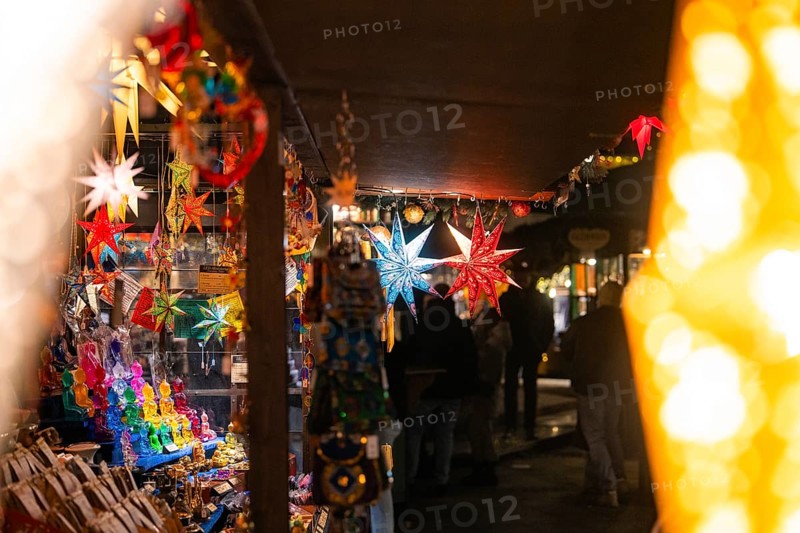 Various colourful stars hanging in a festively illuminated market stall at night, Christmas market Ludwigsburg, Germany