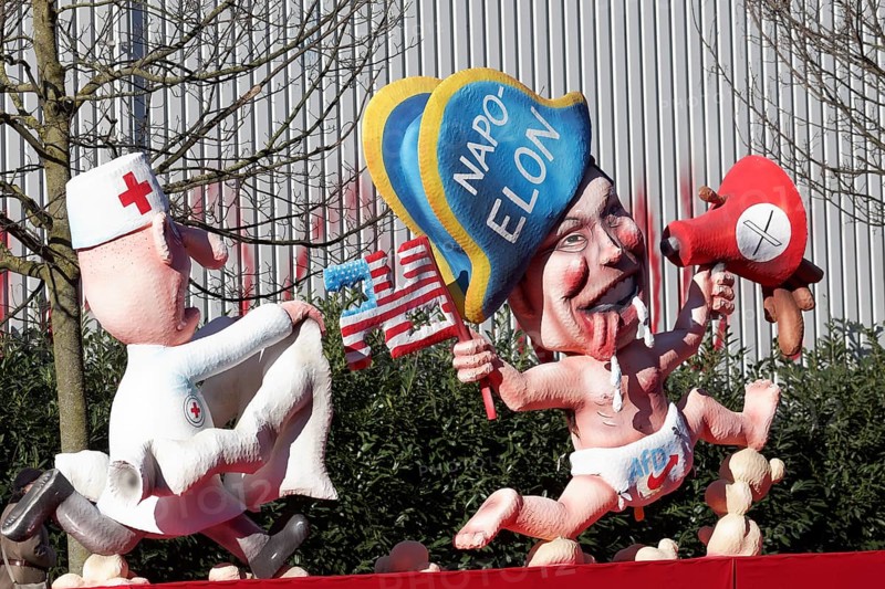Elon Musk with Napoleon hat, wears nappy trousers with AfD logo, carer with straitjacket runs behind him, papier-mâché figures, Jacques Tilly theme float, Rosenmontagszug 2025, Düsseldorf, Rhineland, North Rhine-Westphalia, Germany