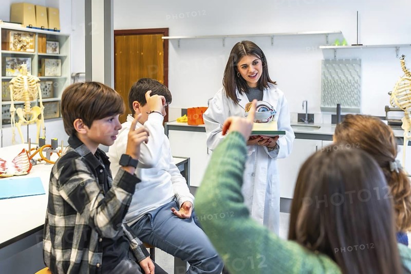 Science teacher explaining human eye anatomy to high school students using a model during a biology lesson in the school laboratory