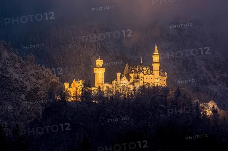 A castle stretches majestically in the darkness, illuminated against a snow-covered slope, Neuschwanstein, Schwangau, Ostallgäu, Allgäu, Swabia, Upper Bavaria, Bavaria, Germany