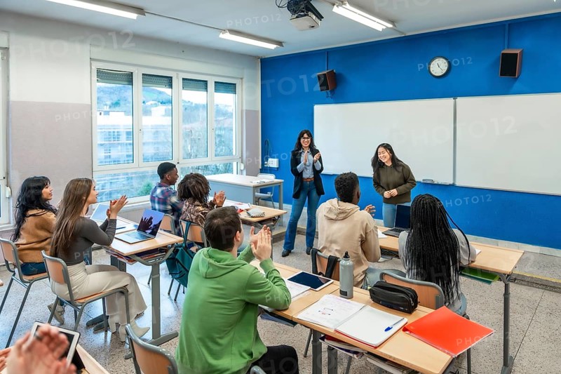 Multi ethnic university students clapping hands after a classmate presentation in a modern classroom