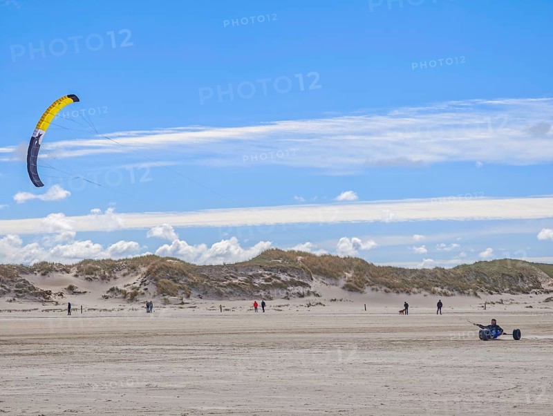 Recreational sport Beach kiting on the edge of the national park and UNESCO World Heritage Site, designated kite area, kite buggy steered with both feet, driver's seat with kiter between rear axle and front wheel, high speed, westerly winds, dunes on the beach, sunshine and blue sky, Sankt Peter-Ording, Schleswig-Holstein, Germany
