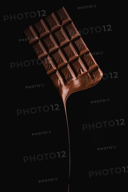 A floating chocolate bar with melting drops on a black background