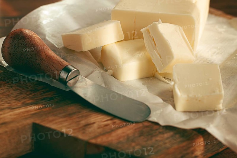 Butter briquette, on wrapping paper, wooden chopping board and butter knife, breakfast, rustic style, no people
