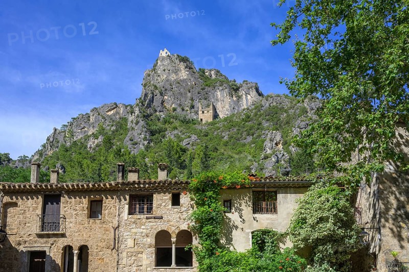 View from Place de Liberte over old stone house up to ruins in the rocks, Saint-Guilhem-le-Désert, Département Hérault, France