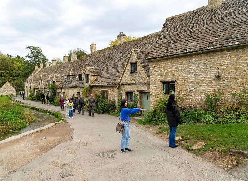 Tourists visiting famous Cotswold buildings at Arlington Row, Bibury, Gloucestershire, England, UK