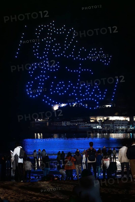 Drone show at night at the Christmas inauguration in San Sebastian, Gipuzkoa. Illuminated city and the figure of Happy Holidays