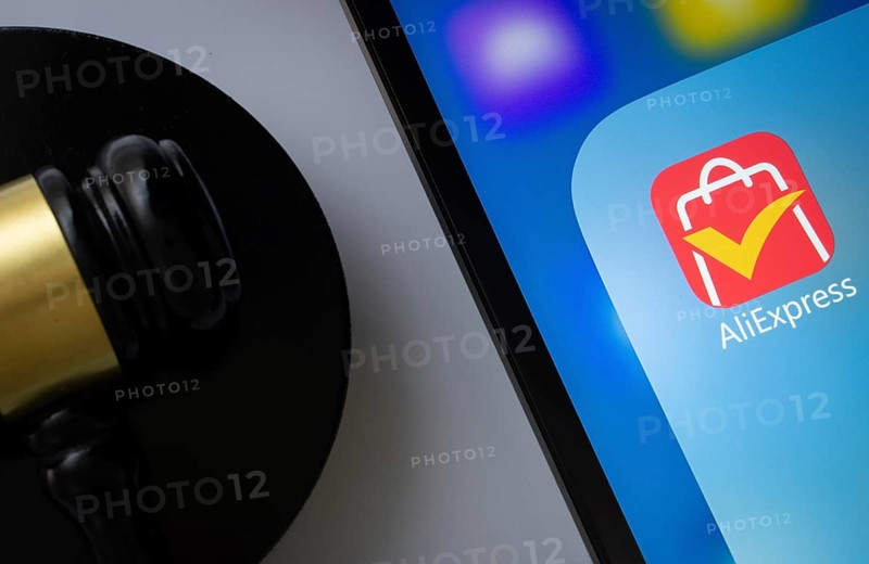 A close up of an iPad screen displaying the AliExpress app alongside a judge's gavel