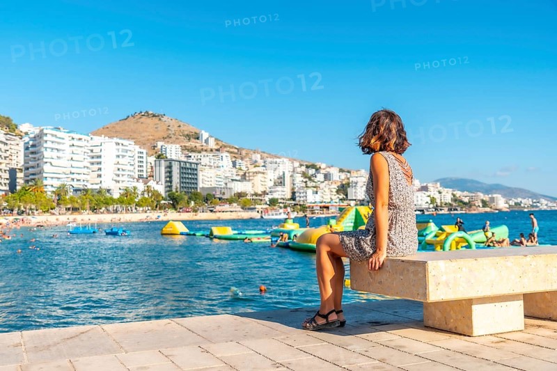 A woman tourist on vacation sitting by the sea at Saranda Beach on the Albanian Riviera in Sarande, Albania