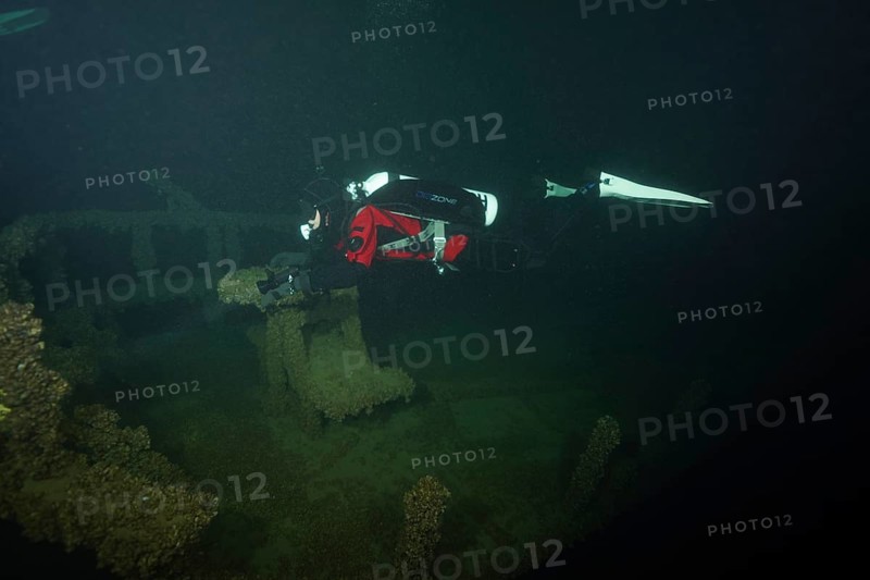 A diver examines the remains of a shipwreck overgrown with mussels, quagga triangle mussel (Dreissena rostriformis bugensis), invasive species, in the quiet darkness, dive site wreck of the Jura, Lake Constance, Bottighofen, Switzerland, Münsterlingen, Germany