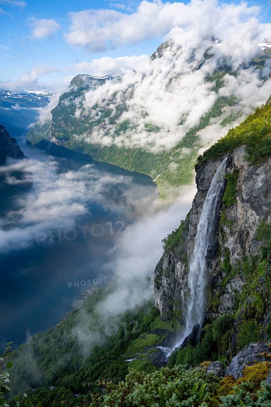 Gjerdefossen waterfall, at Ørnesvingen viewpoint, atmospheric clouds over the fjord in the morning light, at Geirangerfjord, near Geiranger, Møre og Romsdal, Norway