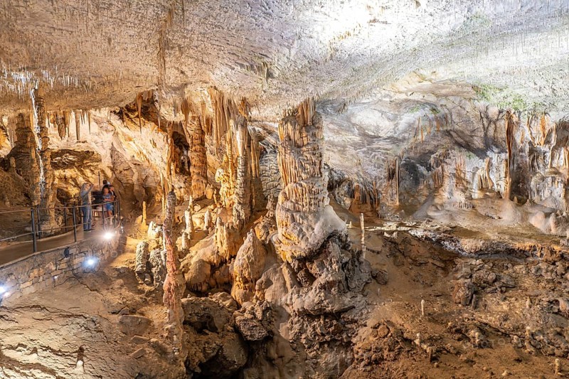 Tourists admiring the magnificent formations of stalactites and stalagmites inside postojna cave, a popular tourist attraction in slovenia