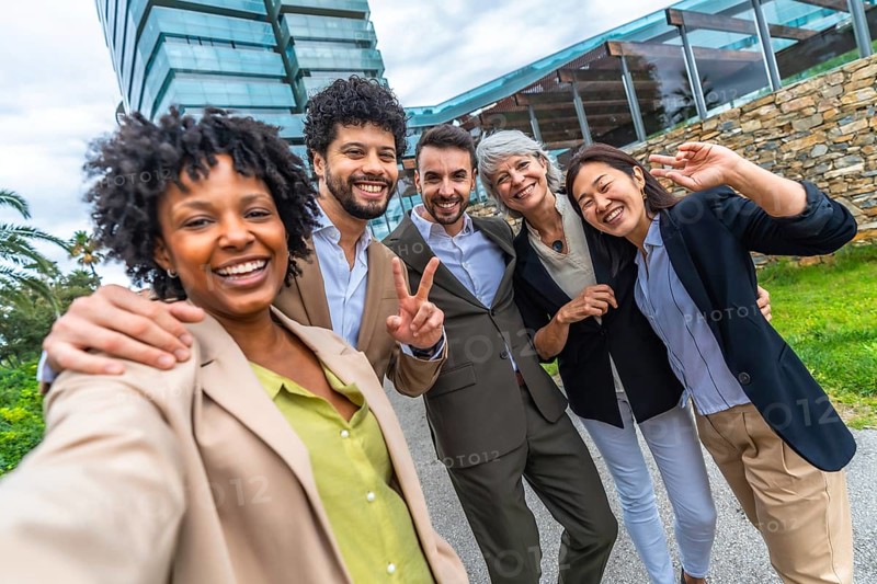 Multi-ethnic business colleagues gesturing success while taking selfie together outdoors in the city