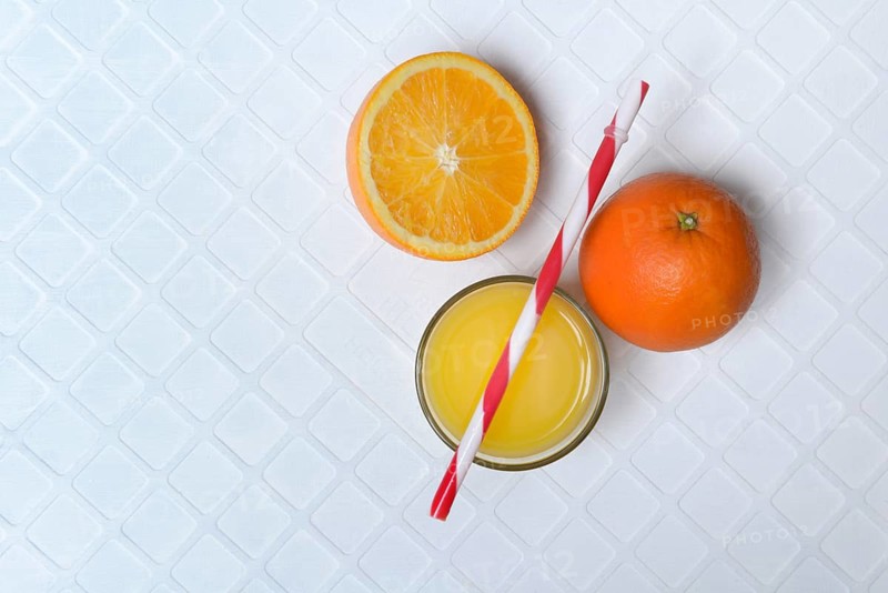 Orange juice in glass and orange, straw